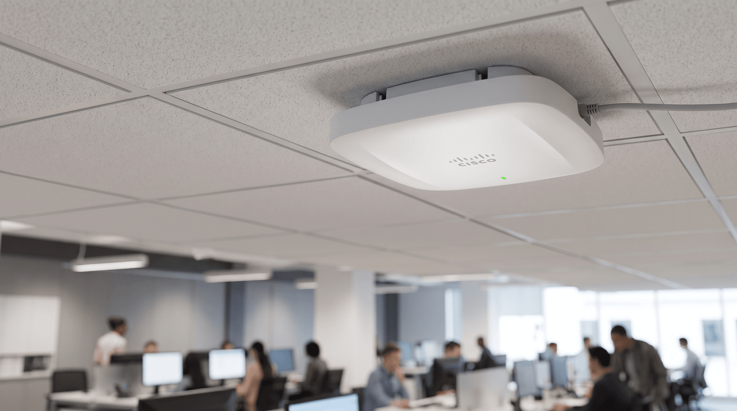 อุปกรณ์กระจายสัญญาณเครือข่ายไร้สาย Cisco Access Point สีขาวติดตั้งอยู่บนฝ้าเพดาน พร้อมไฟสถานะสีเขียว โดยมีฉากหลังเป็นบรรยากาศในสำนักงาน